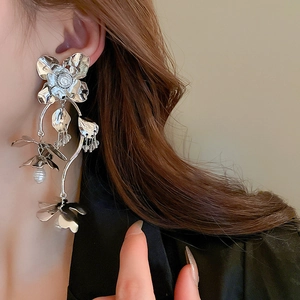 Gros plan sur les boucles d'oreilles fleur en métal avec feuilles argentées et perle