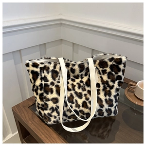 Détail du sac cabas en fausse fourrure léopard avec des anses en cuir blanc sur une table