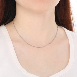 Détail du collier en acier argenté avec perles porté sur le cou d'un mannequin femme