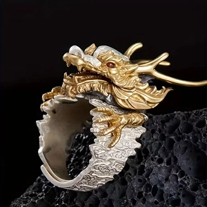 Close-up of golden dragon open ring with red eyes on black volcanic stone