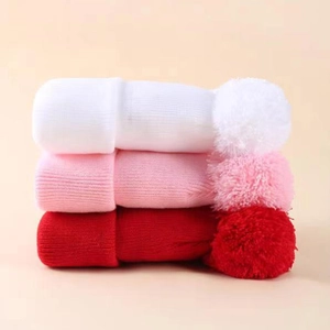 Three-pack knit winter hats in white pink and red with large fluffy double pom-poms