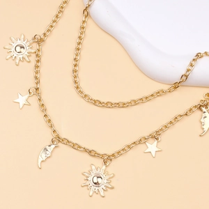 Multilayer gold body chain featuring sun moon and star charms on a white prop pedestal