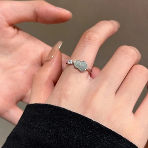 Close-up of silver hollow wave ring with green stone and zircon worn on finger
