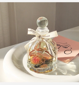 Detail of rose citrus reed diffuser with dried flowers in a glass bottle on a ceramic tray