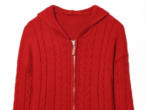 Détail d'un cardigan rouge en maille torsadée avec capuche et fermeture éclair en cuir