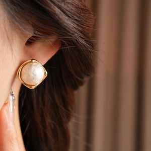 Detail shot of vintage gold plated square earrings with cream baroque pearl on model
