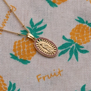 Close-up of gold beaded chain necklace with red zircon religious pendant detail