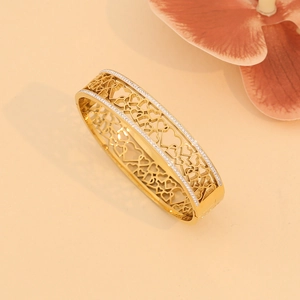 Detailed close-up of golden hollow heart bracelet with crystal pavé stones decoration