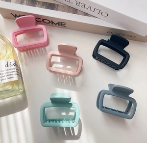 Flat lay of five matte square hollow hair claws in pink, black, and mint green colors