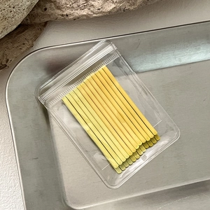 Close-up of set of twelve yellow metal bobby pins in a clear plastic retail bag