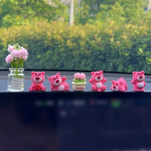 Pink Lotso bear resin figurines in various poses on dashboard with Good Luck flower pot