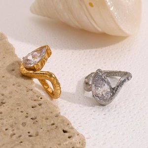 Detail of tear-shaped stones on gold and silver rings over natural beige stone