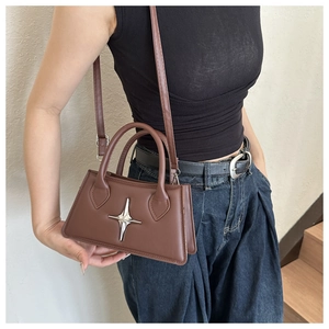 Side view of dark brown leather crossbody bag with silver star ornament and adjustable strap
