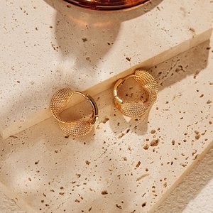 Textured 18K gold plated brass twisted hoop earrings on neutral stone background
