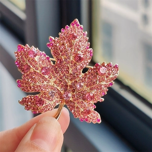 Detailed view of luxury maple leaf brooch with pink crystals and gold base setting