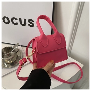 Rosa Mini-Handtasche aus PU-Leder mit Überschlag, handgehalten in einem Café-Ambiente
