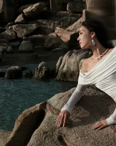 Detail showing elegant pearl jewelry set with necklace and earrings on a textured beach