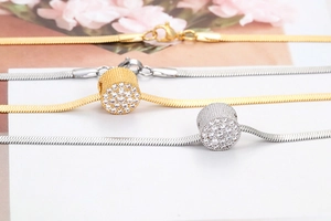 Close-up of gold and silver snake chain necklaces with sparkling pavé crystal pendants