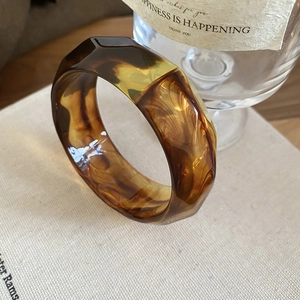 Detailed view of geometric amber resin bangle with marbled pattern on textured surface