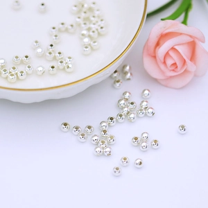 Close-up of polished silver round spacer beads for DIY jewelry making on white tray