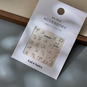 Dettaglio di adesivi nail art 3D segni zodiacali con cornici in metallo e perle su carta