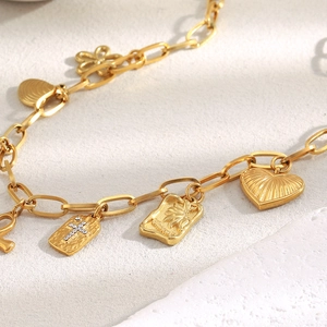Detail of 18K gold plated chain bracelet featuring cross, palm tree, and heart charms