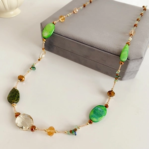 Detail shot of boho beaded long necklace with green agate and crystal glass on velvet box