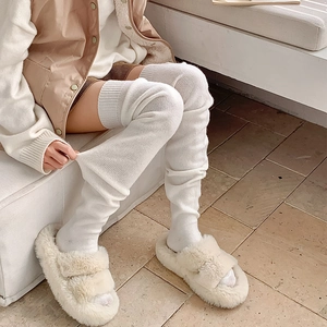Detail of white cable knit over-knee socks with ribbed cuffs for winter warmth