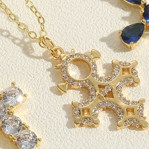 Macro shot of 14K gold plated cross pendant with shimmering white zircon stones