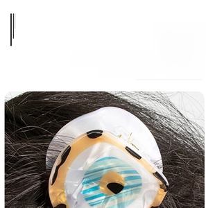 Detailed view of the evil eye claw clip with blue stripes and dots on blonde hair