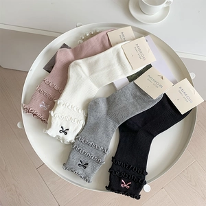 Close-up of four-color crew socks with ruffle edges and delicate bow embroidery