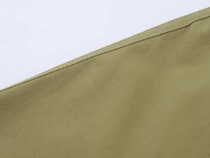 Détail du tissu tissé vert armée montrant des coutures de qualité et une texture sergée