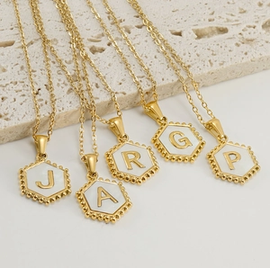 Detailed macro of five 18K gold-plated hexagonal initial necklaces with beaded edges