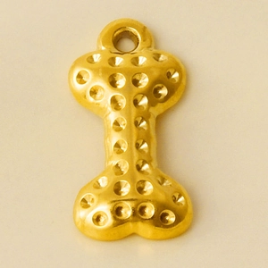 Detailed close-up of a golden bone-shaped pendant with a unique dotted texture finish