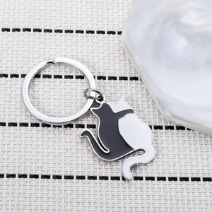 Minimalist black and white cat embrace enamel keychain on woven mat background