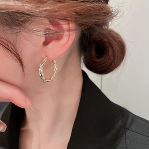 Gros plan d'une boucle d'oreille torsadée plaquée or avec zircons sur un mannequin