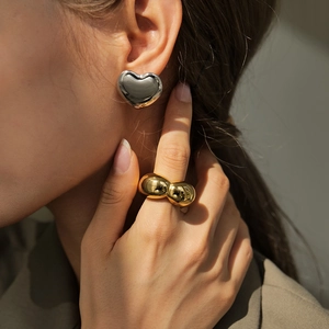 Lifestyle-Aufnahme eines 18K vergoldeten Blasenrings und silberner Herzohrringe am Model