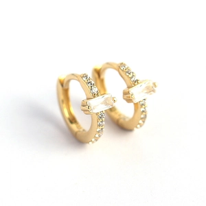 Minimalist gold huggie earrings with baguette cut zircon and pavé setting on white background