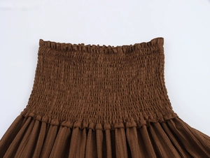 Close-up of smocked elastic waistband and wrinkled texture on brown vacation skirt