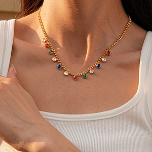 Close-up of golden necklace with colorful teardrop gemstone pendants on model neckline