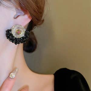 Detail of vintage flower earrings with crystal accents and black beaded tassels on model