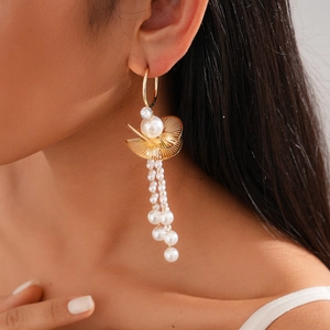 Detail view of gold earrings with pearl tassels and lotus leaf fan-shaped studs