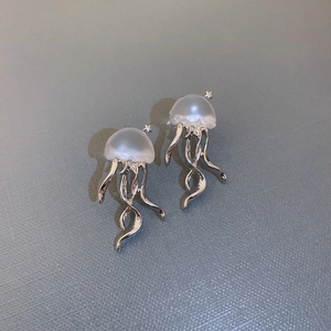Détails macro des boucles d'oreilles méduse avec tentacules argentées et dômes