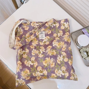 Dettaglio della borsa tote in tela viola a fiori con etichetta tessuta e accessori