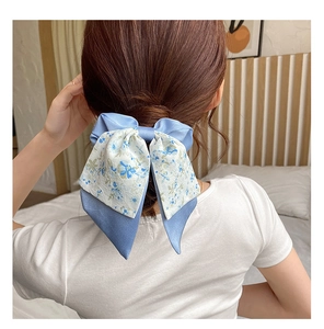 Floral print bow hair scrunchie with blue fabric layers shown on a model hairstyle
