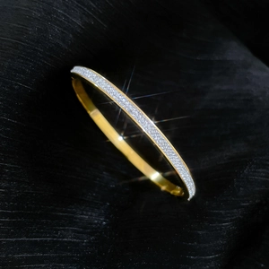 Detailed view of luxury gold titanium steel bangle with full diamond pavé on black silk
