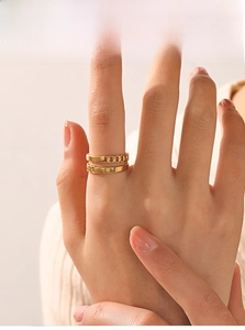 Close-up of stacked 18K gold plated Cuban chain ring and slim band on female finger