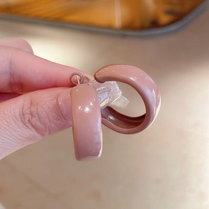 Detailed close-up of C-shaped matte dusty pink hoop earrings with glossy enamel finish