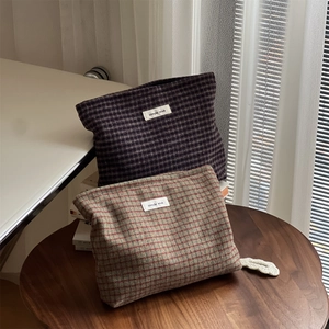 Close-up of retro plaid tweed makeup bags with woven texture and simple wish label