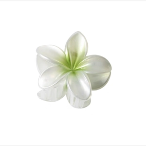 Detail of frangipani hair claw clip showing resin texture and green gradient center